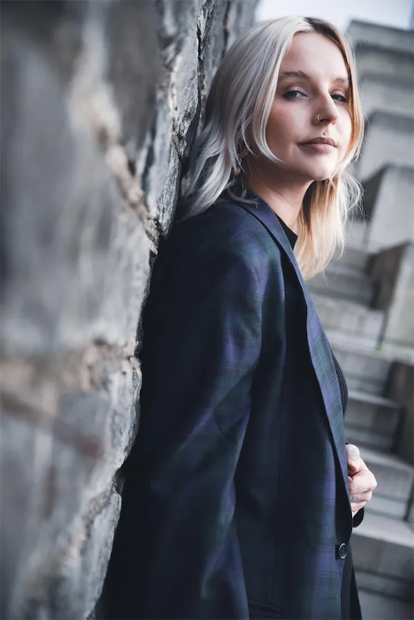 Portrait von Luisa Hüpeler wie sie cool an einer Mauer lehnt